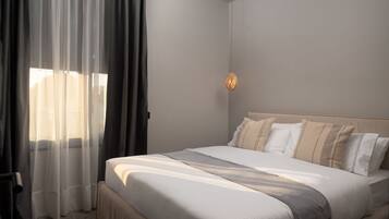 A neatly made bed with a headboard, a bedside table, and a wall-mounted light fixture.