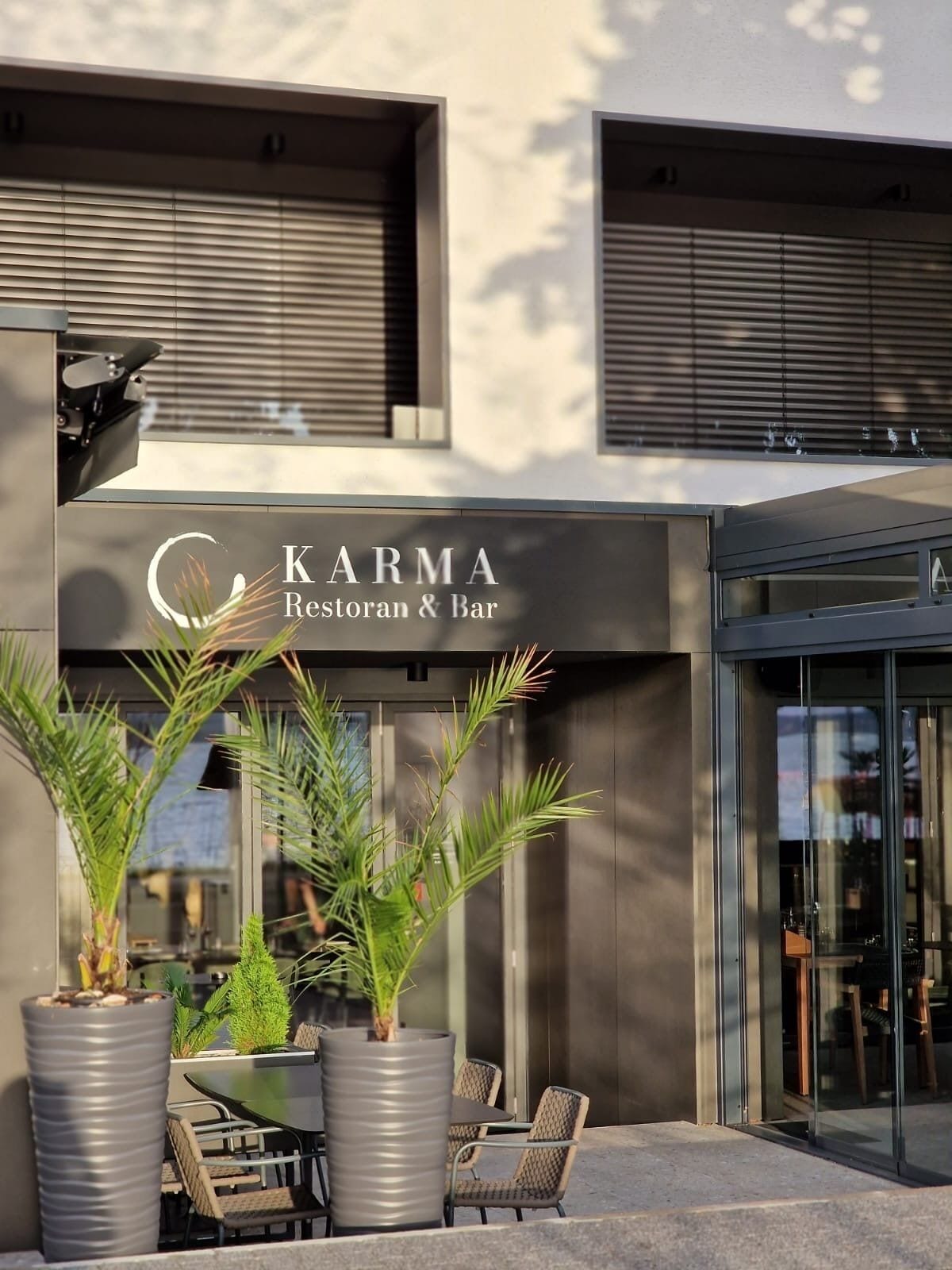 Un restaurant appelé KARMA, doté d’une terrasse et agrémenté de plantes en pot.