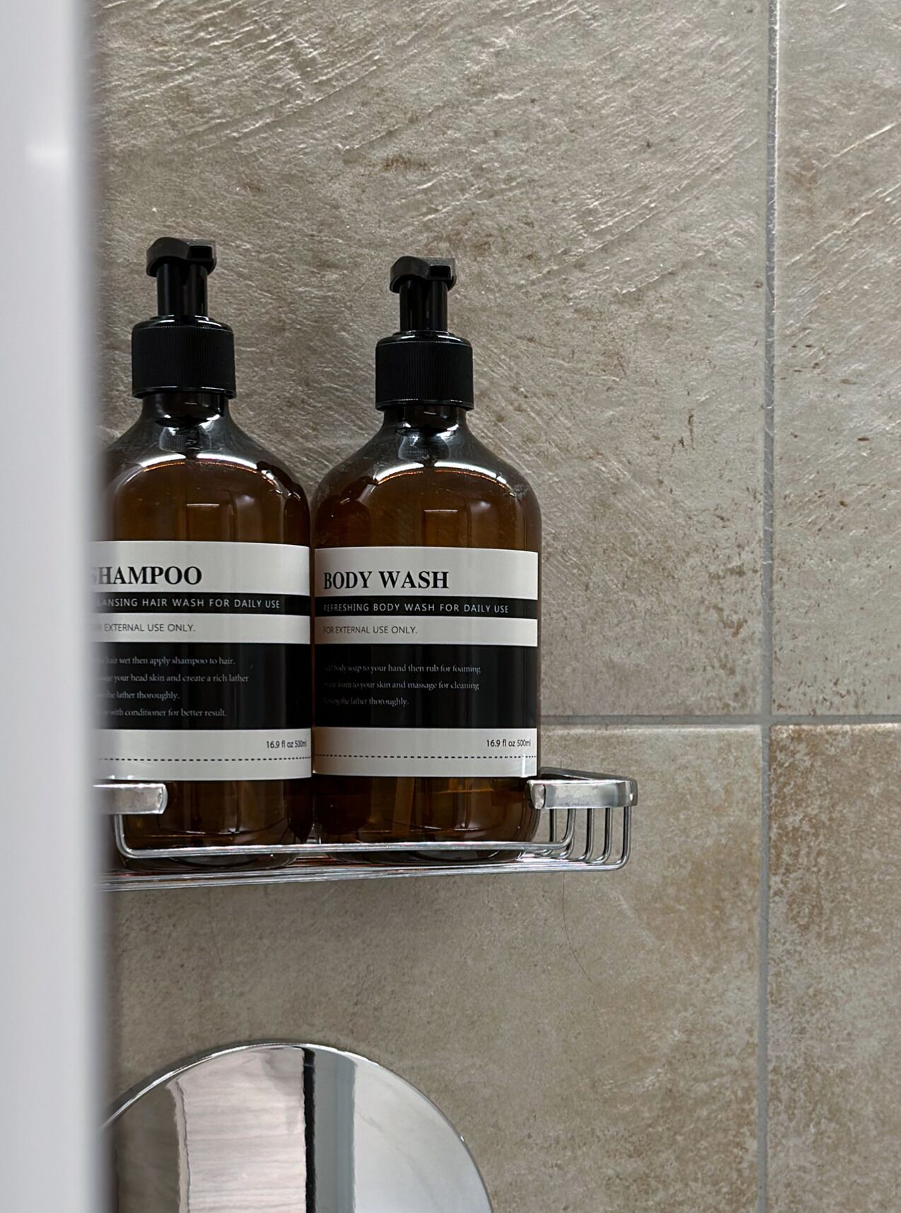 Deux bouteilles de shampoing et de gel douche sur une étagère dans la salle de bain.