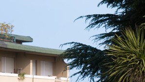 A building with a flat roof, balconies, and a well-maintained garden with various plants.