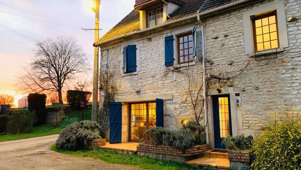 A stone building with a large front door, windows with shutters, and a well-maintained garden. - La Maison bleue (Cuncy-lès-Varzy)