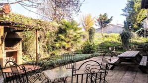 A patio with a table and chairs, surrounded by greenery and a stone wall. - La Maison bleue (Cuncy-lès-Varzy)