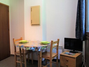 A small dining area with a table, chairs, a television, and a cabinet.