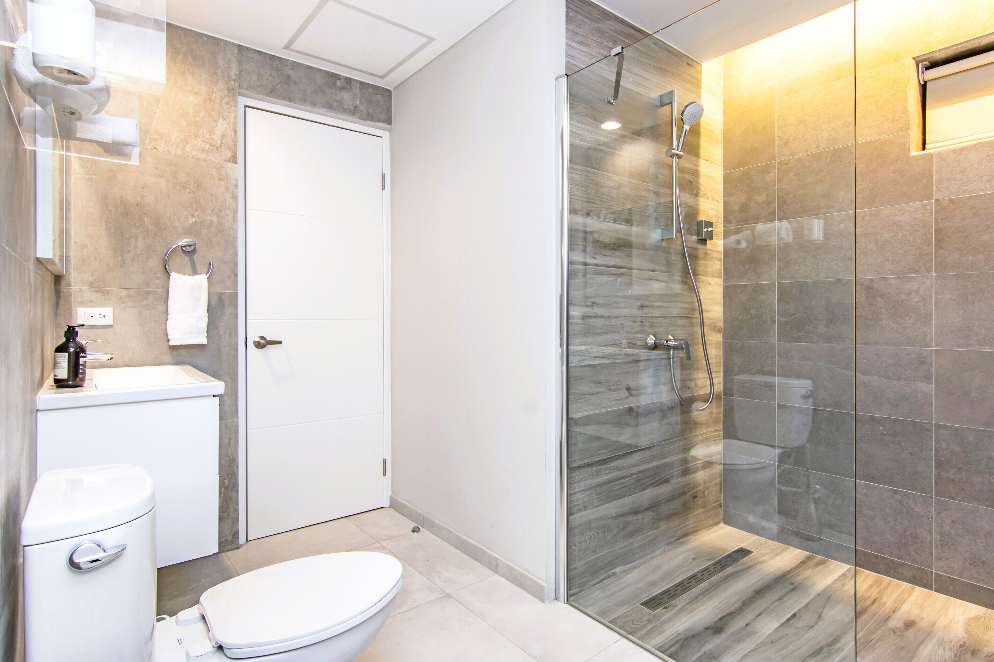 A modern bathroom with a toilet, sink, and glass-enclosed shower.