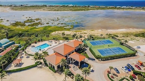 Un complexe hôtelier doté d’une piscine, de courts de tennis et offrant une vue sur la plage.