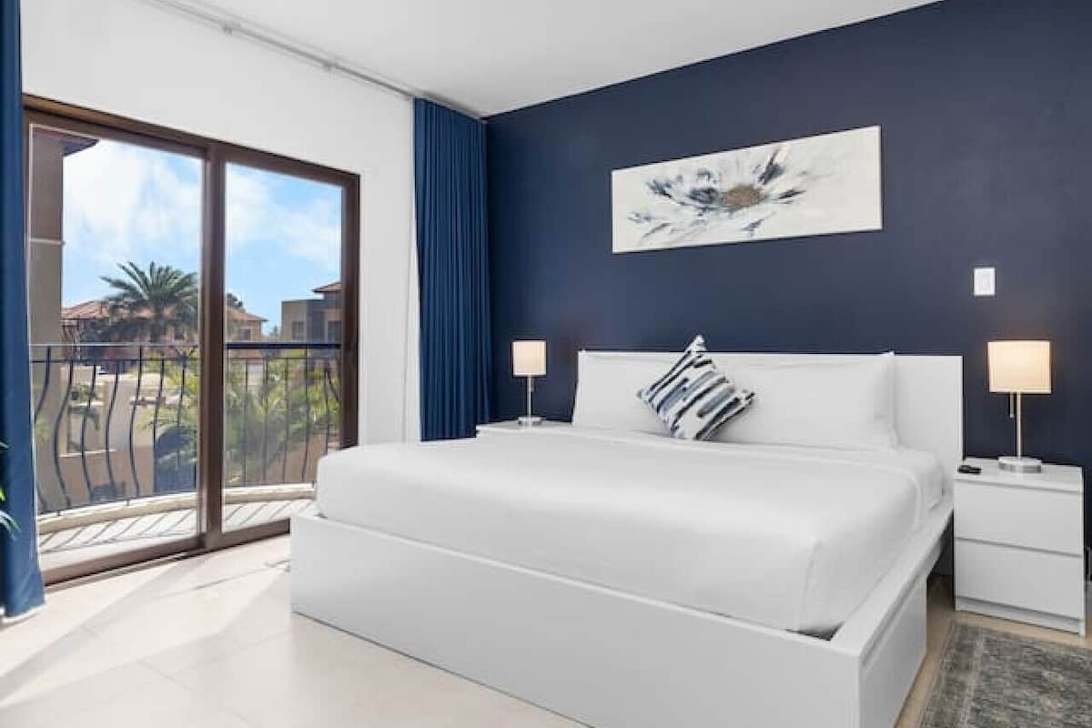 Ein modernes Schlafzimmer mit einem großen Bett, einem Balkon mit Blick und einer Deckenleuchte.