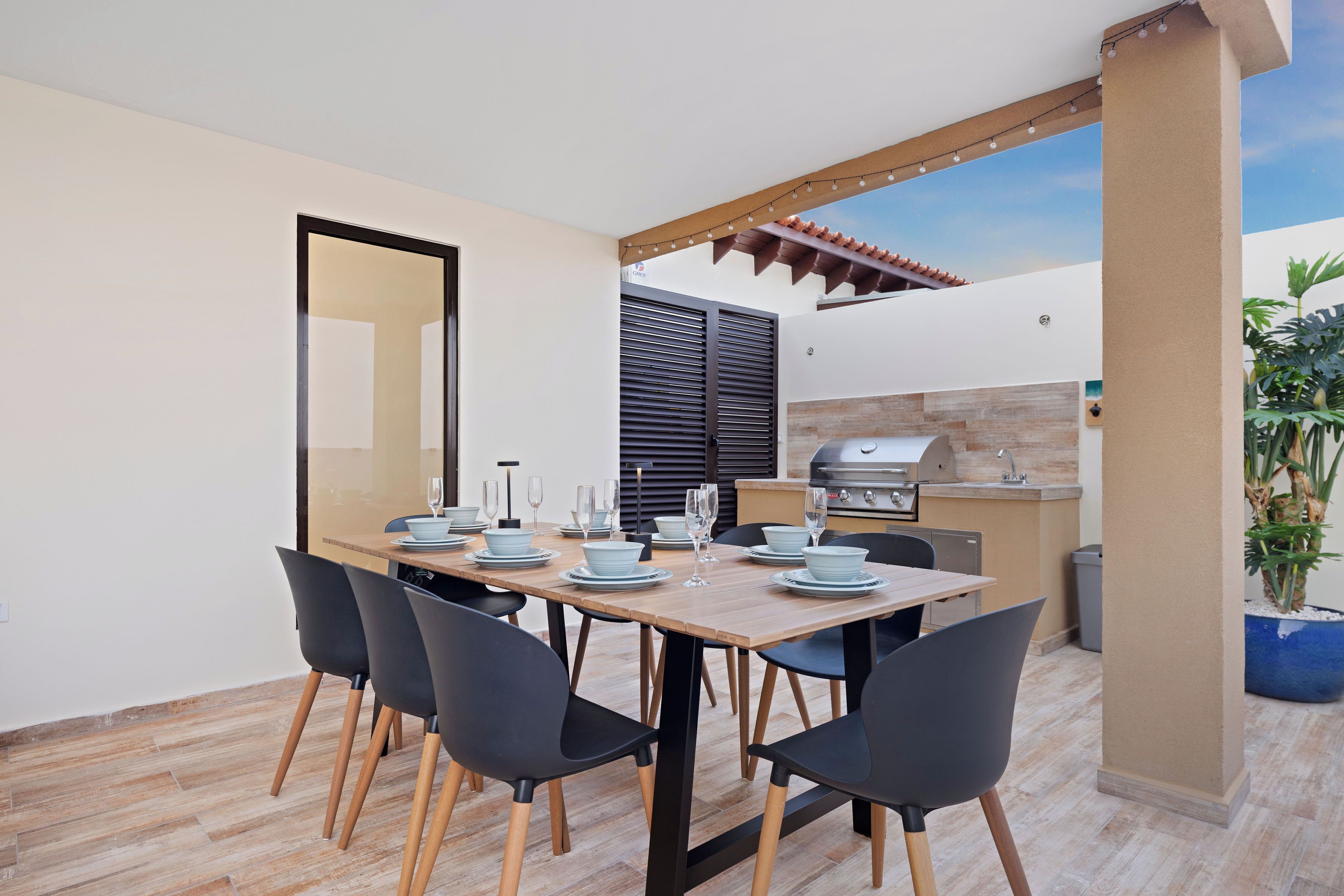 Una cocina moderna con una parrilla, mesa de comedor con sillas y una planta en maceta.
