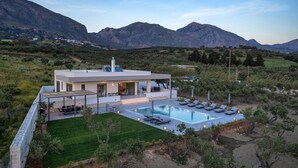 Uma casa moderna com piscina, cercada por montanhas e vegetação.