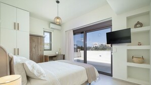 Quarto moderno com uma cama grande, uma escrivaninha, uma cadeira, televisão e varanda com vista.