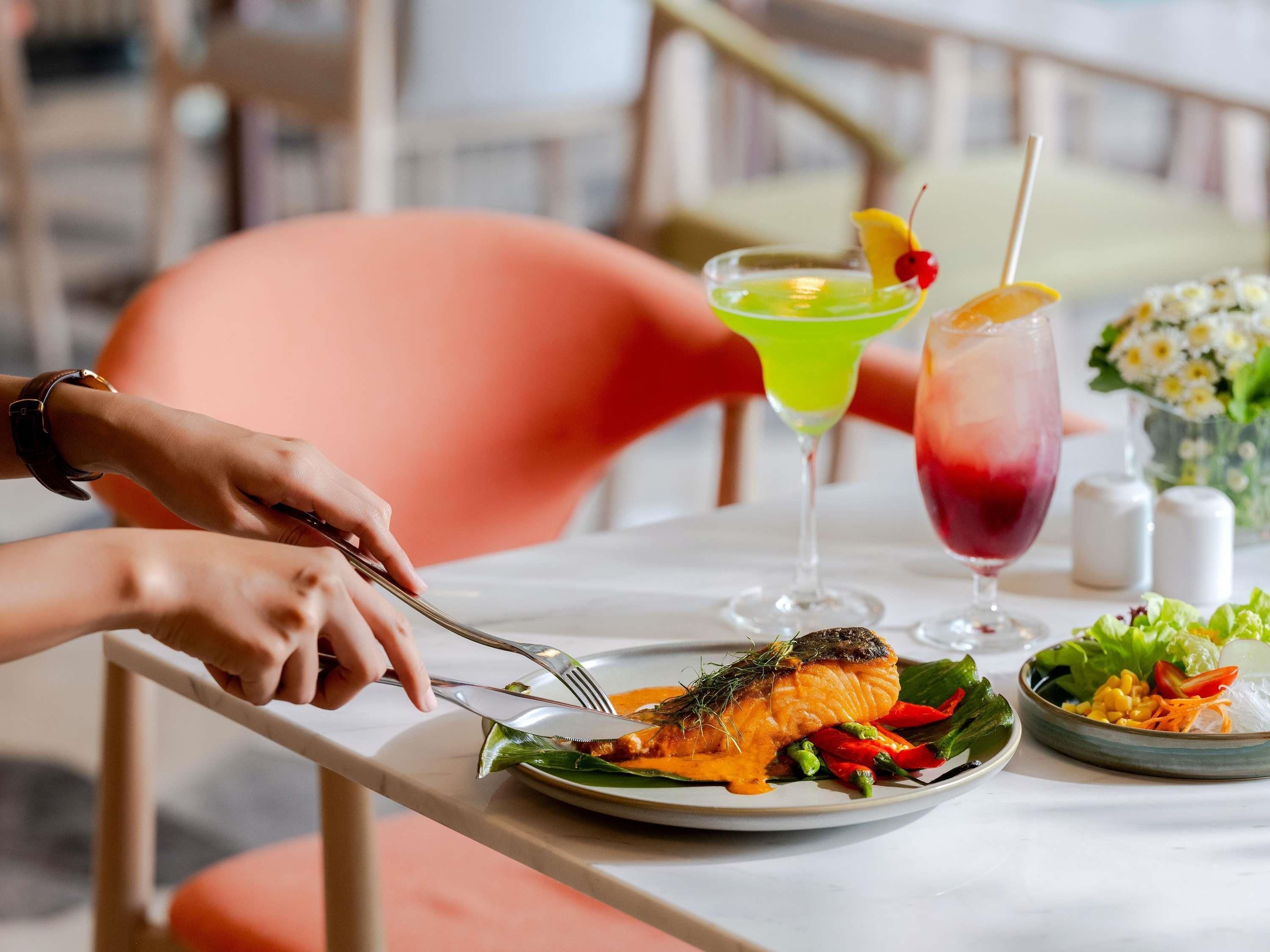 Una mesa de comedor con un plato de comida, una copa de cóctel y una ensalada.