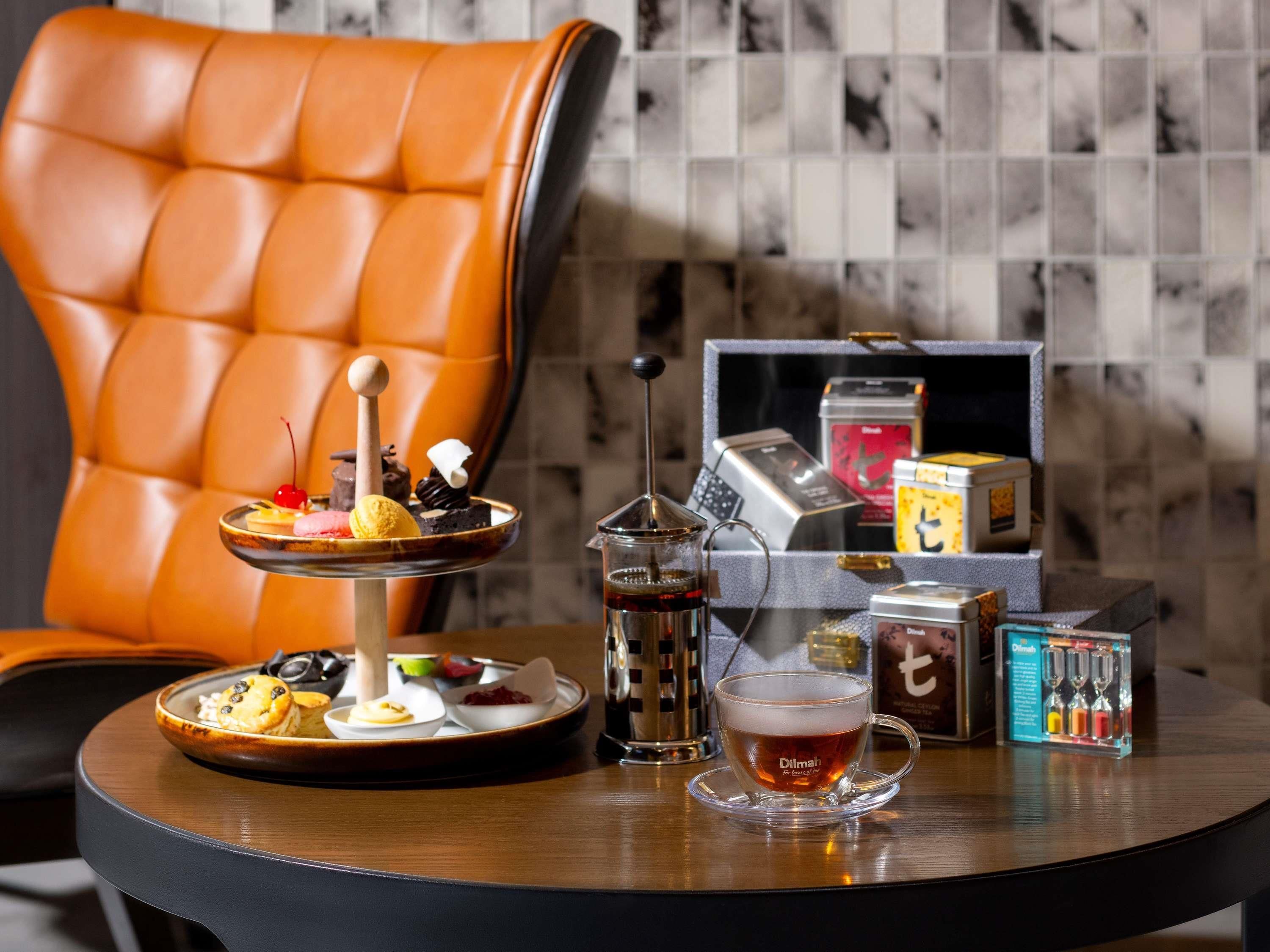 Une table à manger avec un service à thé, une assiette de pâtisseries et une machine à café.