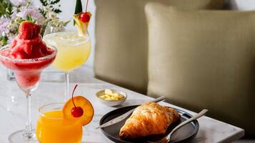 Ein Tisch mit einem Dessertgetränk, einem Fruchtsaft und einem Croissant auf einem Teller.