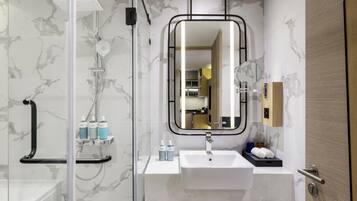 A modern bathroom with a glass-enclosed shower, a white sink, and a mirror with a black frame.