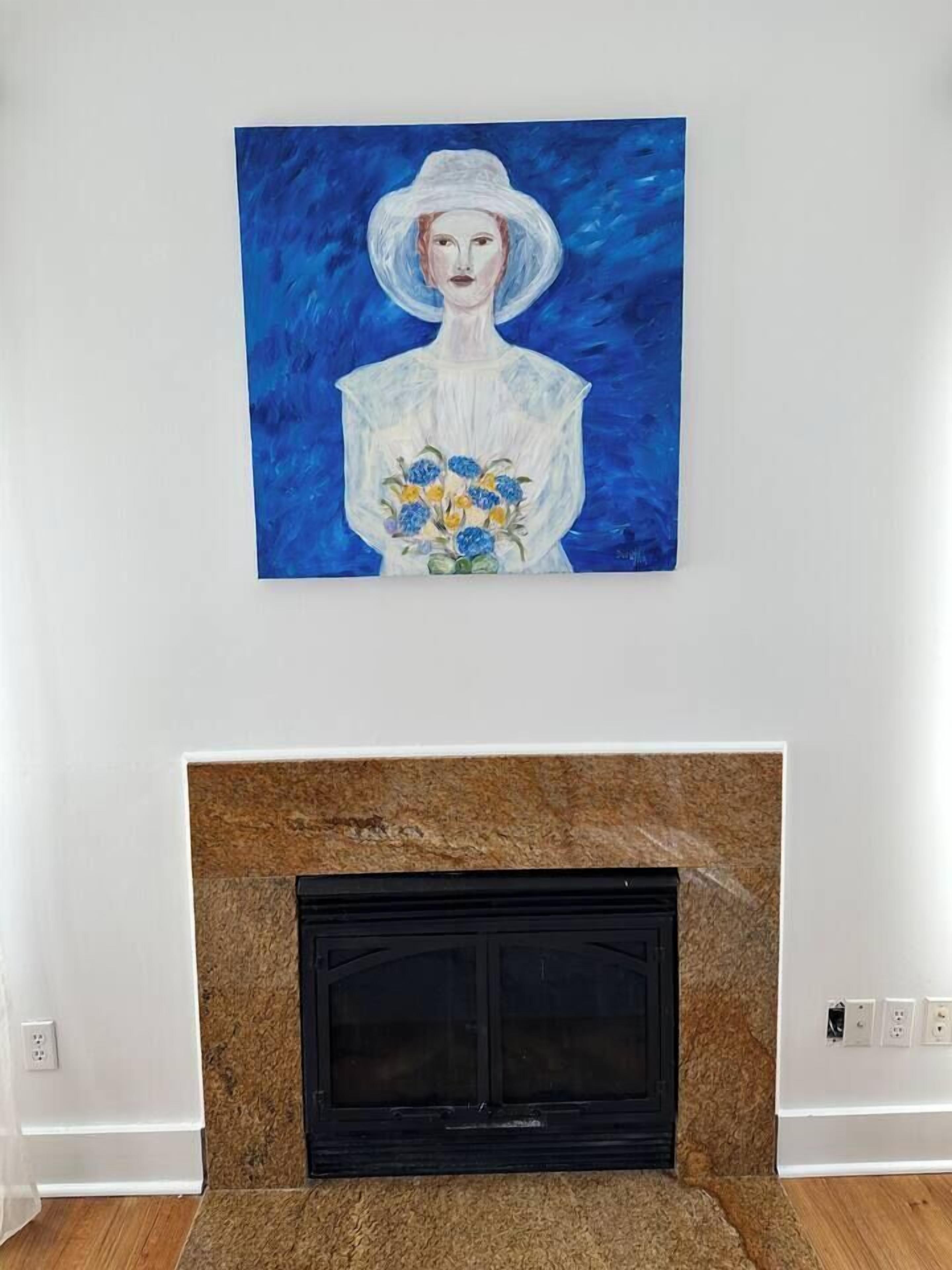 Ein Gemälde einer Frau mit Blumen an einer weißen Wand über einem Kamin.