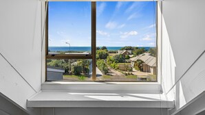 A window with a view of a coastal area, including houses and greenery. - Pohara Beach Escape - Pohara Beach Holiday Home (Pohara Beach)