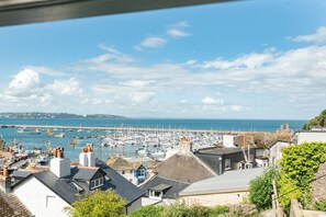 Une ville côtière dotée d’un port de plaisance, de maisons aux toits inclinés et d’un ciel dégagé.