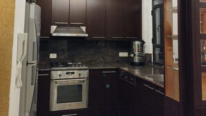 Une cuisine dotée de meubles en bois foncé, d’appareils électroménagers en acier inoxydable et d’un luminaire suspendu moderne.
