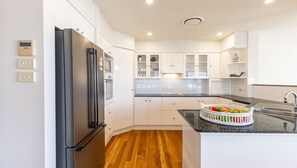 A modern kitchen with white cabinets, a black refrigerator, and a wooden floor. - 74A Sergeant Baker Drive - comfortable duplex with beautiful distant water views (Corlette)