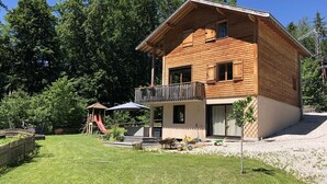 Et træhus med balkon, rutsjebane og et legeområde.