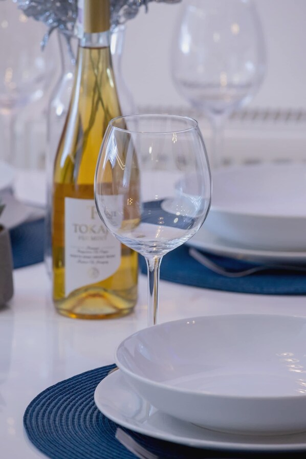 A table setting with a wine bottle, a wine glass, and a white plate.