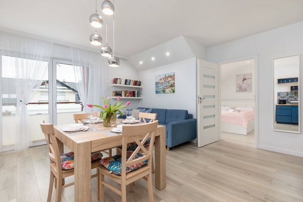 An open-plan living and dining area with bright decor, a kitchen, and wooden flooring.