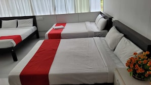 A hotel room with two beds, each with white bedding and red accents, and a vase of orange flowers on a bedside table. - Oxygen Rainforest Resort (Thodupuzha)