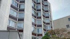 Ein mehrgeschossiges Gebäude mit moderner Architektur, das durch eine Reihe von Balkonen und große Fenster gekennzeichnet ist.