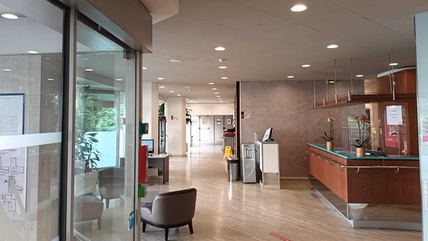 Eine moderne Lobby mit Empfangstresen, Sitzgelegenheiten und einer Glaswand mit Informationspostern.