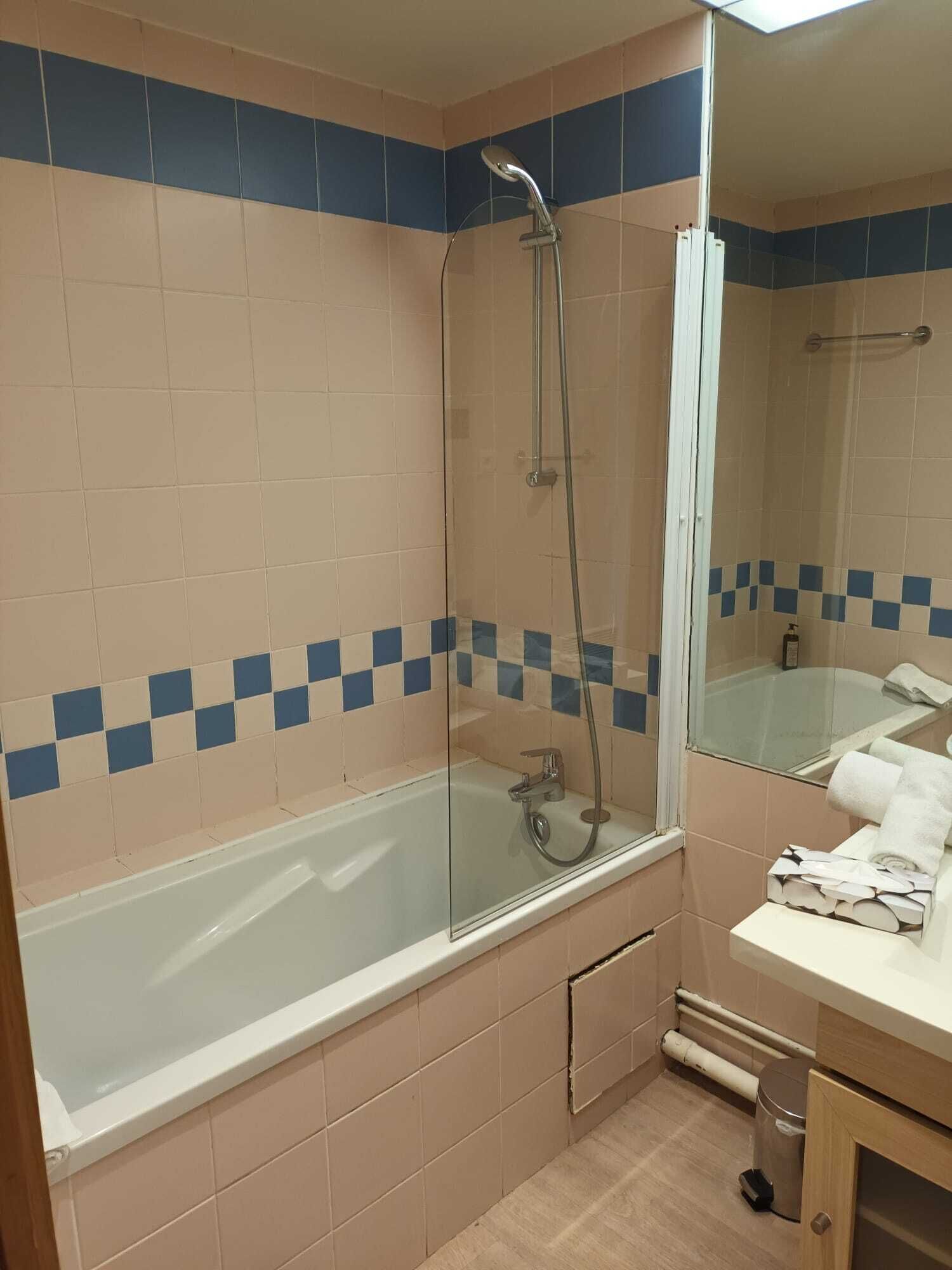 Un baño con ducha envuelta en vidrio, bañera y tocador con toallas.