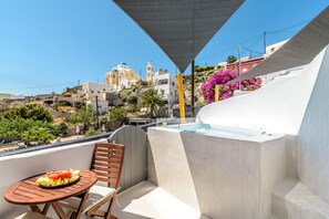 A balcony with a table set for a meal, a chair, and a hot tub. - Anila Suites (Santorini)
