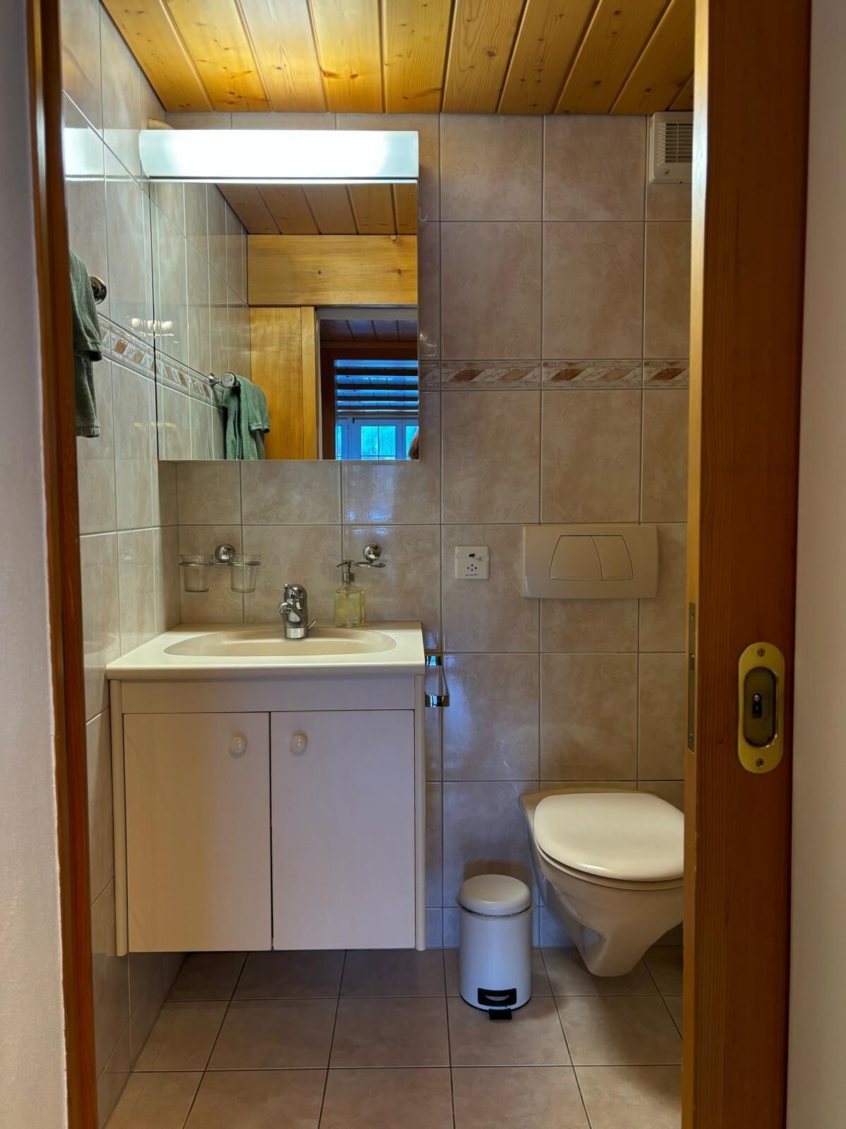 A compact bathroom with a white sink, mirror, and toilet.
