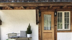 Une porte en bois avec une fenêtre, un banc avec des coussins et une plante en pot.