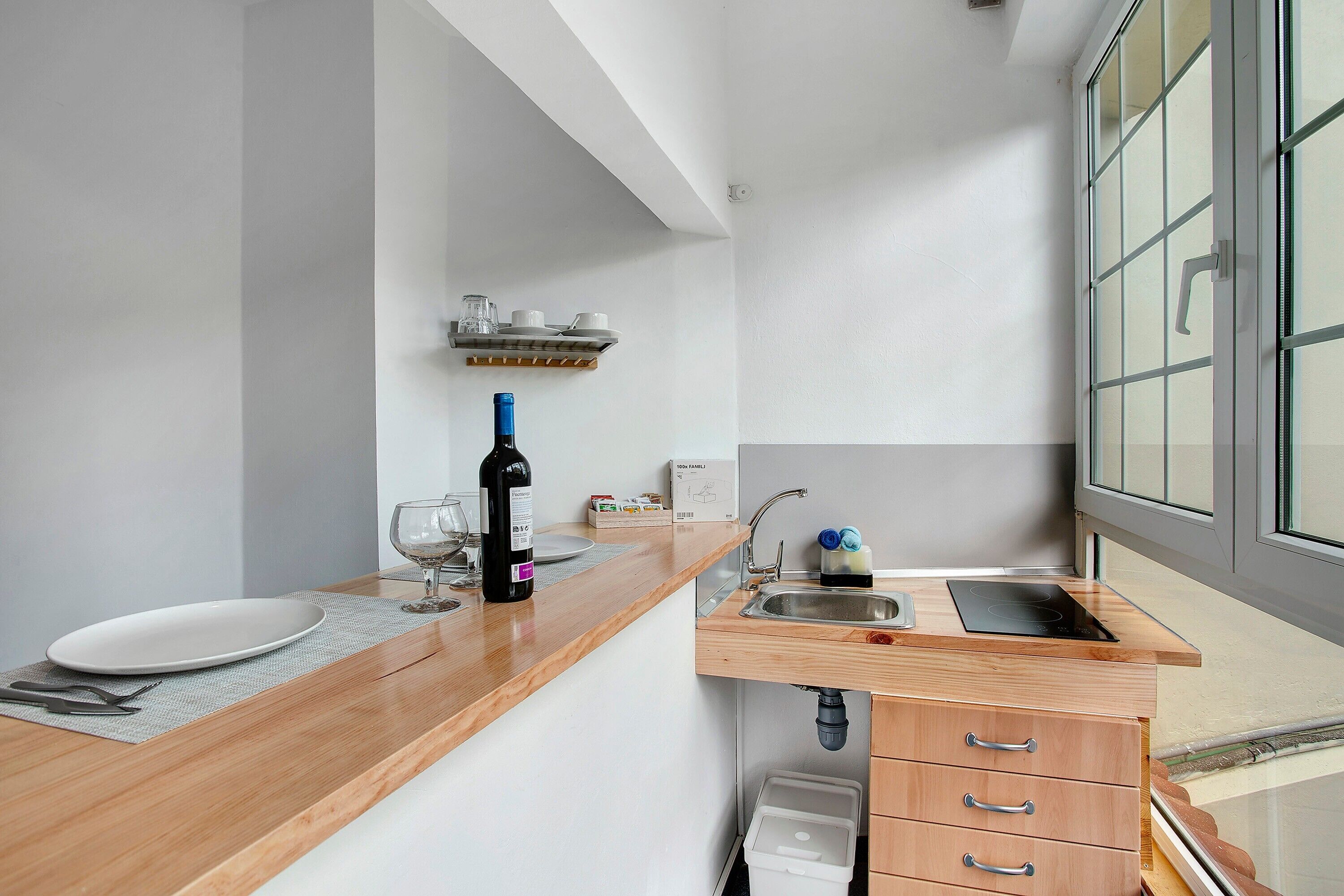A modern kitchen with a wooden countertop, a sink, and a window with frosted glass.