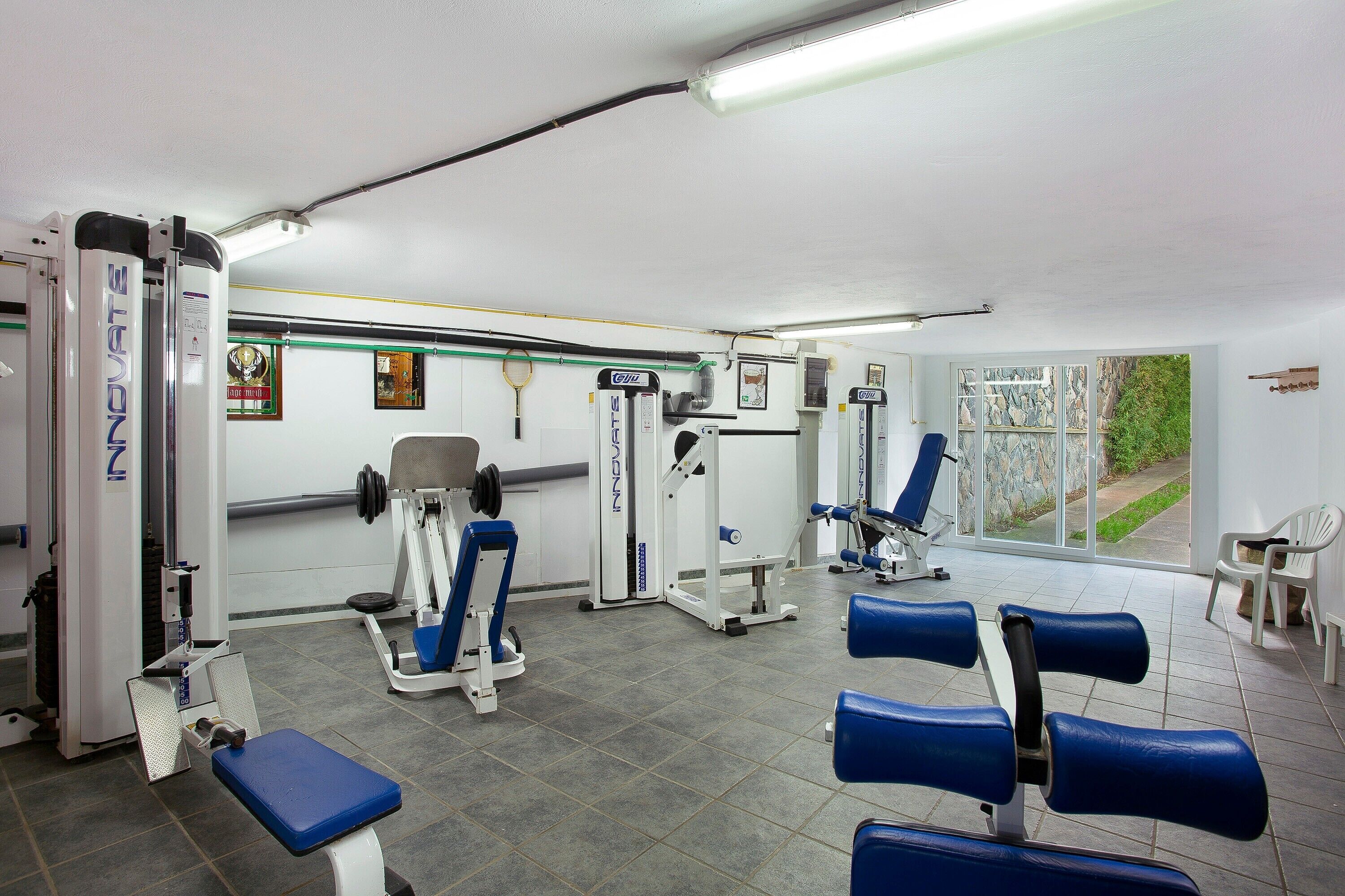 Un gimnasio con equipo de ejercicio, una banca y una ventana con vistas.