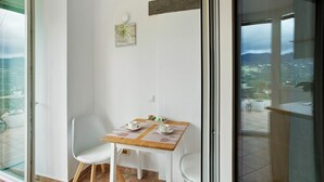 Ein Balkon mit Tisch für zwei Personen, einem Stuhl und Blick auf die Stadt.