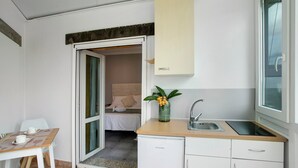 Eine kompakte Küche mit Spüle, kleinem Kühlschrank und Essbereich mit Tisch und Stühlen.