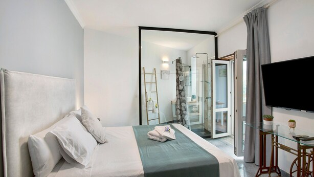 Ein Hotelzimmer mit Bett, Fernseher, Glastisch und angrenzendem Badezimmer.