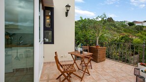 Ein Balkon mit Tisch, Stühlen, einer Topfpflanze und Blick auf die umliegende Landschaft.