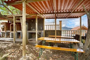An outdoor patio area with wooden tables and benches, a corrugated metal roof, and a view of a mountainous landscape. - Holiday Apartment "Carmelo Y Carmela 3" with Mountain View, Private Terrace & Wi-Fi (teror)