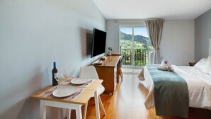 A hotel room with a bed, a desk with a computer, a TV, and a dining area with a table set for two. - Holiday Apartment "Carmelo Y Carmela 4" with Mountain View, Private Terrace & Wi-Fi (teror)