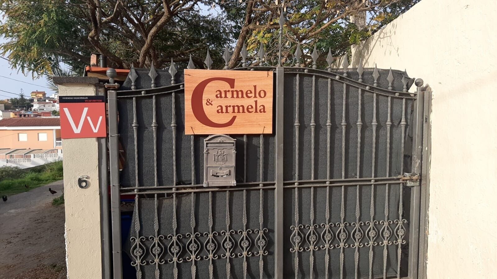 Een poort met een bord waarop 'Carmelo & Carmela' staat.