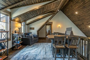 Une pièce de style loft avec des poutres apparentes, un canapé, une table à manger avec des chaises et une grande fenêtre.