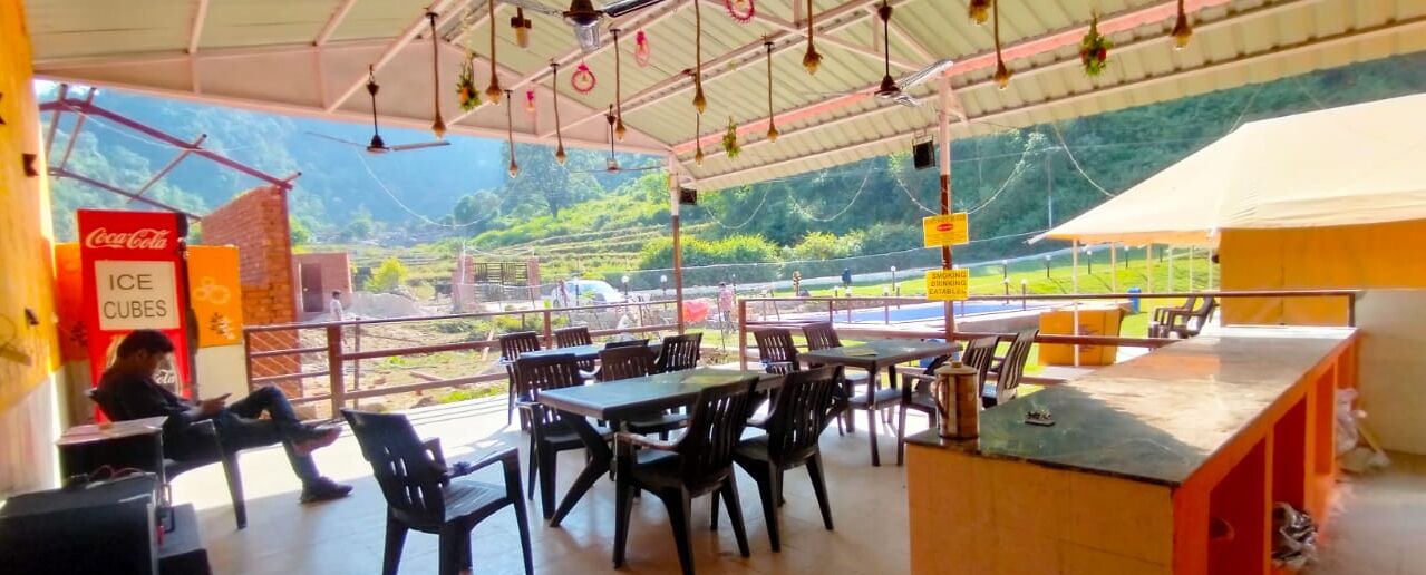 Un espace extérieur aménagé avec des tables et des chaises, un distributeur automatique de Coca-Cola et une vue sur les montagnes.