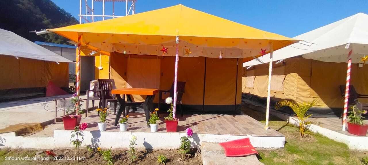 A series of tents with a central dining area, surrounded by potted plants and outdoor seating.