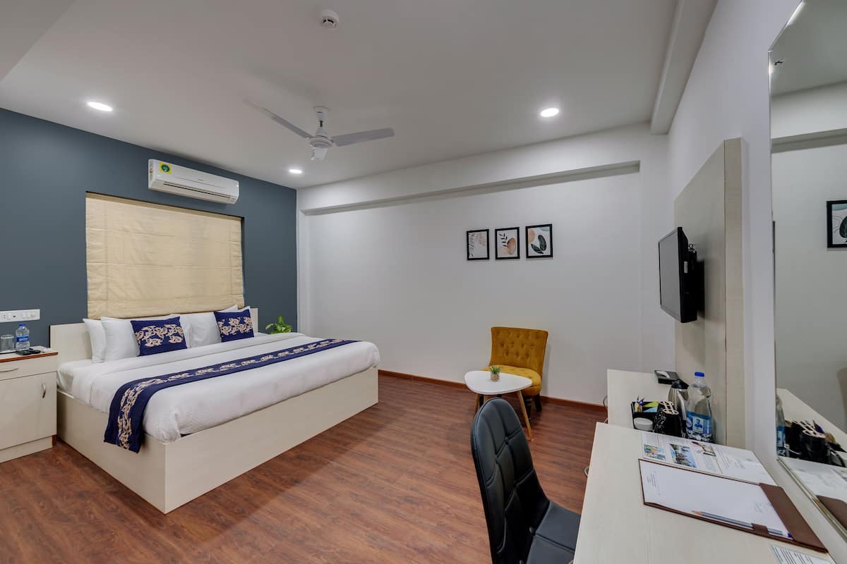 Une chambre d’hôtel équipée d’un lit, d’un bureau, d’une chaise, d’un climatiseur, d’un ventilateur de plafond et d’une télévision.