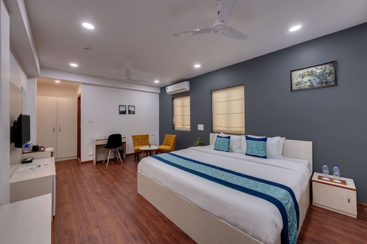 Une chambre d’hôtel équipée d’un lit, d’un bureau, de chaises, d’un ventilateur de plafond et d’un appareil de climatisation.