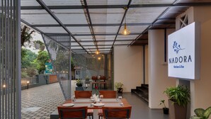 Een restaurant met een modern design, met een overdekt terras met tafels en stoelen.