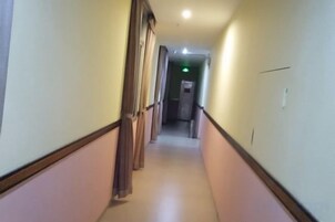 Un pasillo estrecho con puertas a ambos lados, que conduce a una habitación al final.