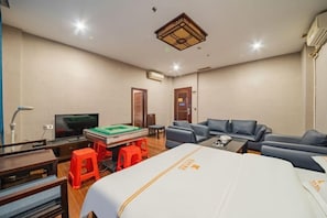 A hotel room with a bed, a sofa, a television, a pool table, and a desk.