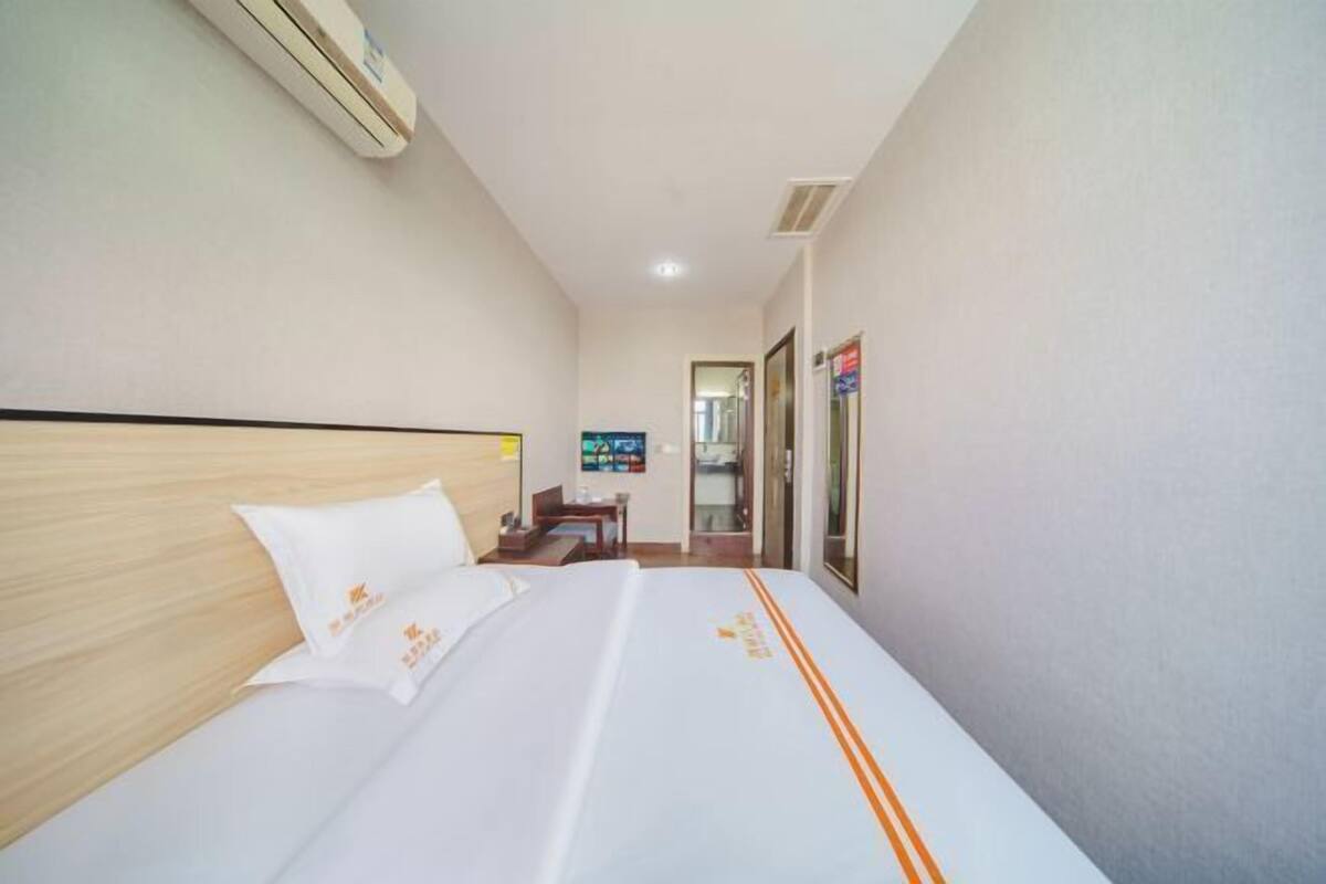 A hotel room with a bed, a desk, and a chair. There is a window and a door.